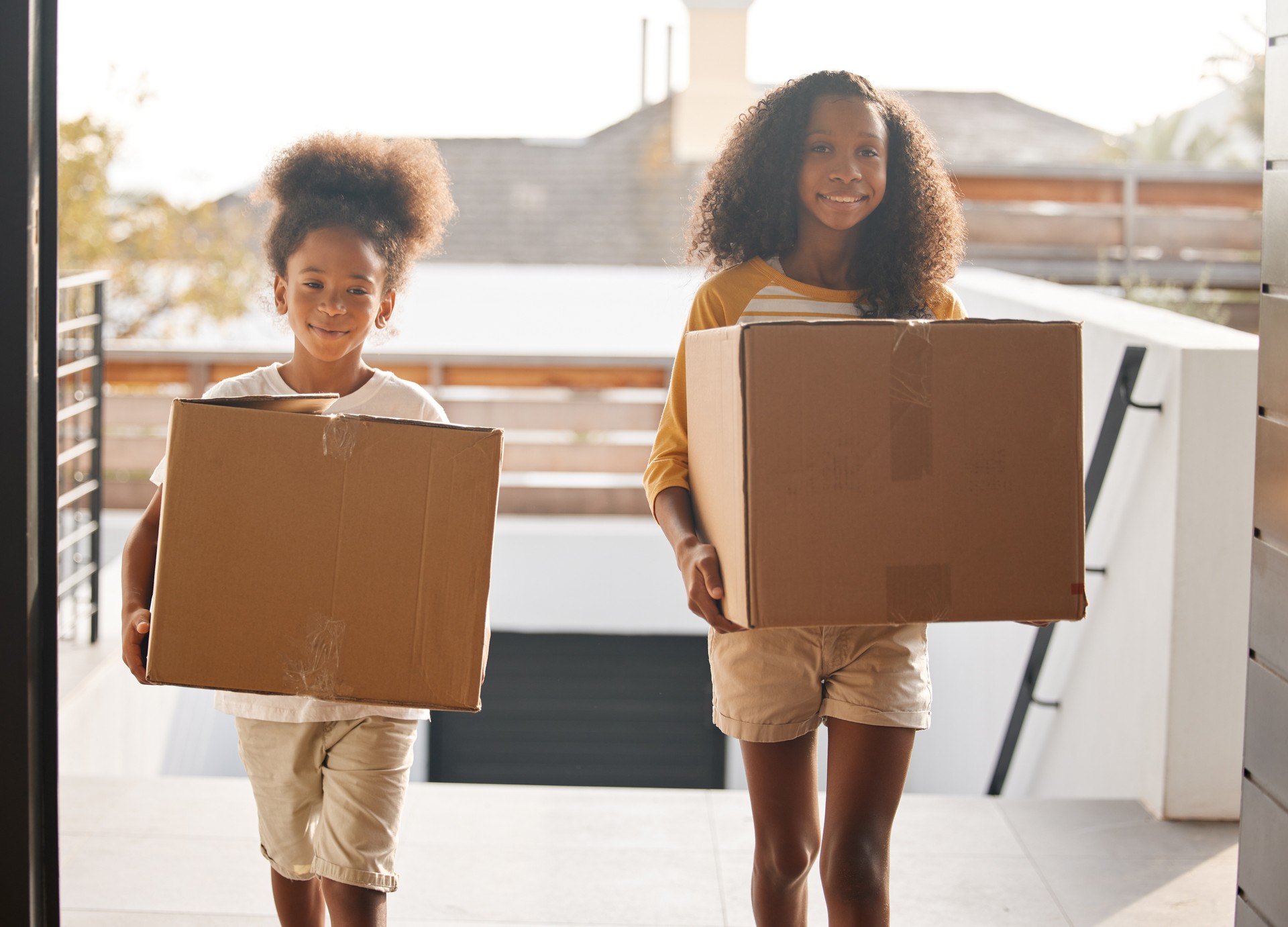 Shot of two sisters carrying boxes into their new home